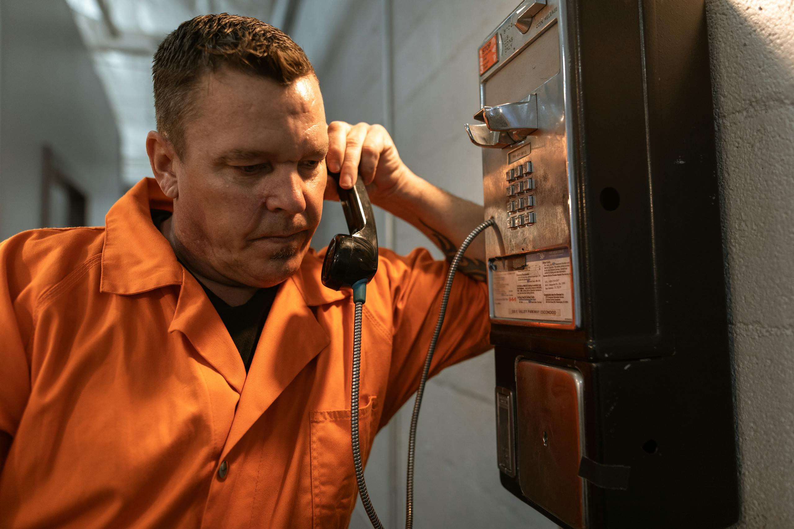 Man in Orange Button Up Shirt Holding Telephone