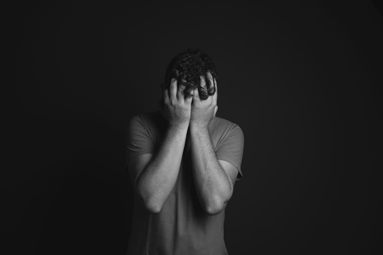 Gray scale Photo of Man Covering Face With His Hands