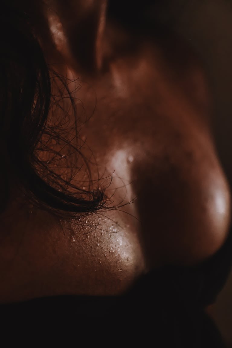 High angle of crop anonymous lady in black outfit with bare wet chest and dark hair