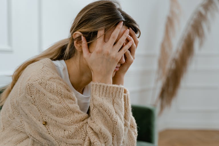 Woman Sitting with Hands Covering Her Face