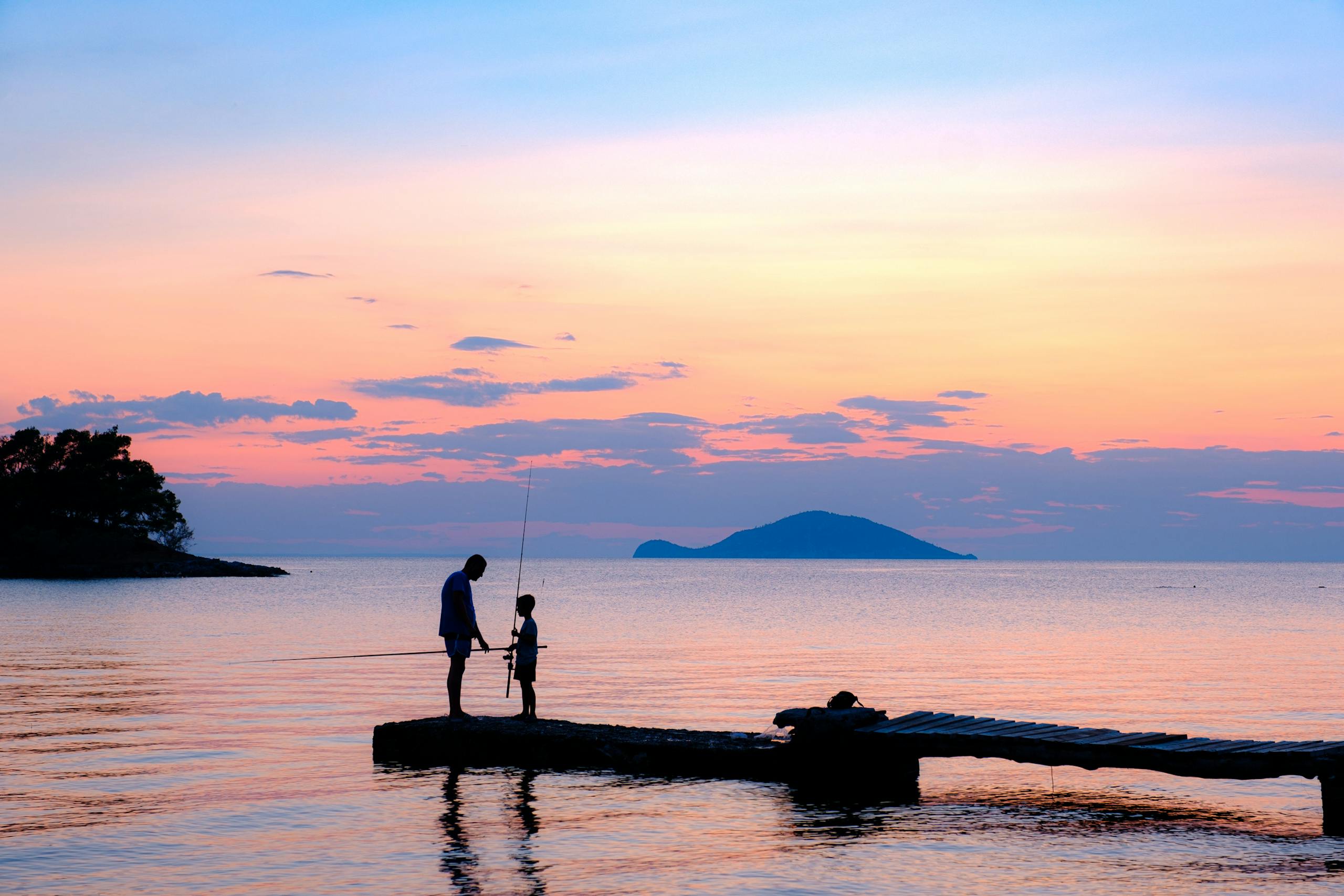 Father and Son Fishing on Sea Shore at Sunset