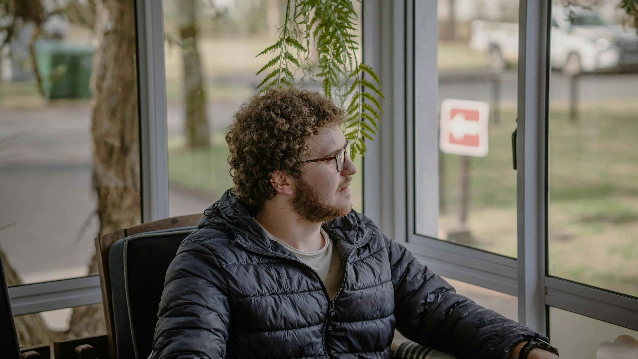 Man in Eyeglasses Sitting in Corner