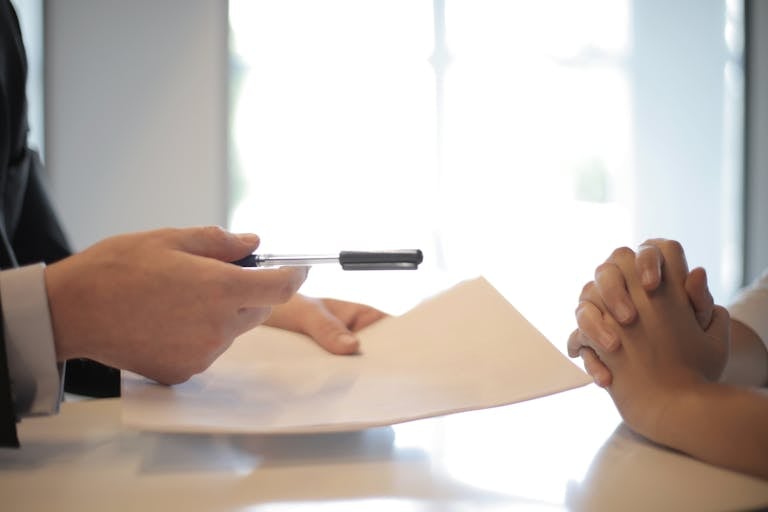 Close-up of a contract signing with hands over documents. Professional business interaction.